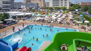 Une grande piscine extérieure dotée de plusieurs couloirs, entourée de chaises longues et de parasols.
