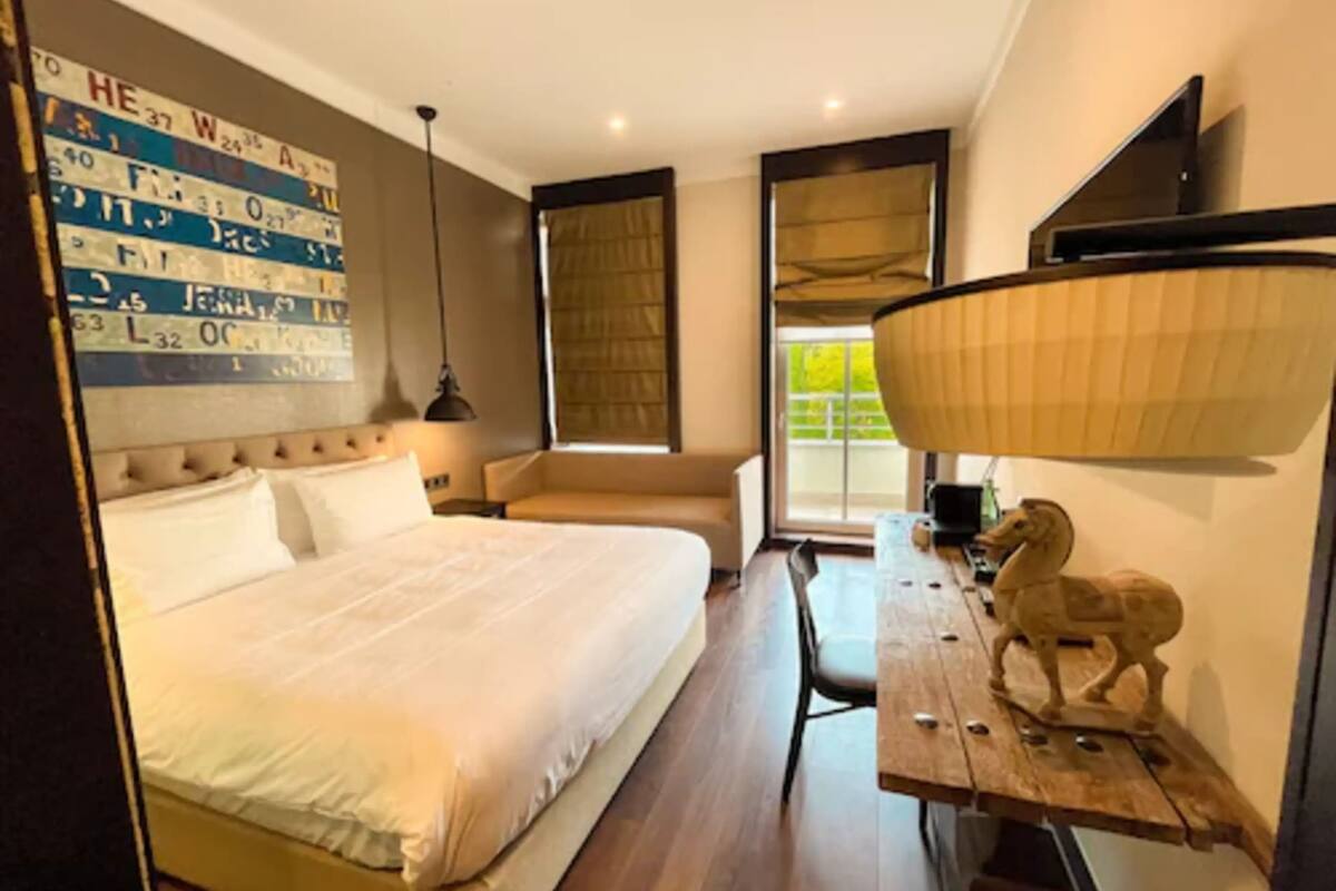 Ein modernes Hotelzimmer mit einem großen Bett, einem Schreibtisch mit Lampe und einer dekorativen Tierfigur.