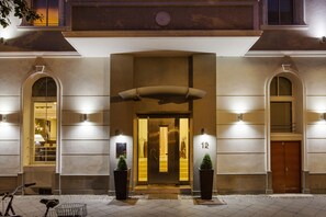 A hotel entrance with a large door, two potted plants, and the number 12 on the wall. - Quentin Design Hotel Berlin (Berlin)