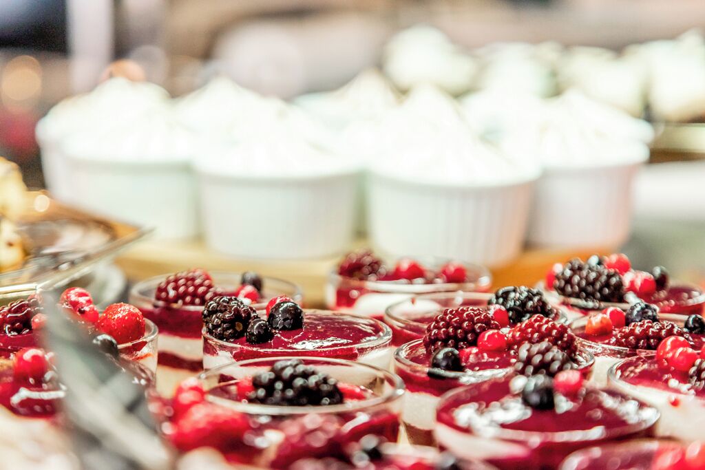 Une variété de desserts, notamment des parfaits garnis de fruits rouges et des petits gâteaux blancs, étaient présentés sur une table.