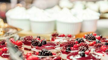 Une variété de desserts, notamment des parfaits garnis de fruits rouges et des petits gâteaux blancs, étaient présentés sur une table.