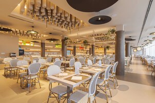 Un restaurante espacioso con techos altos, luminarias modernas y diversas opciones de asientos, incluyendo mesas y sillas.