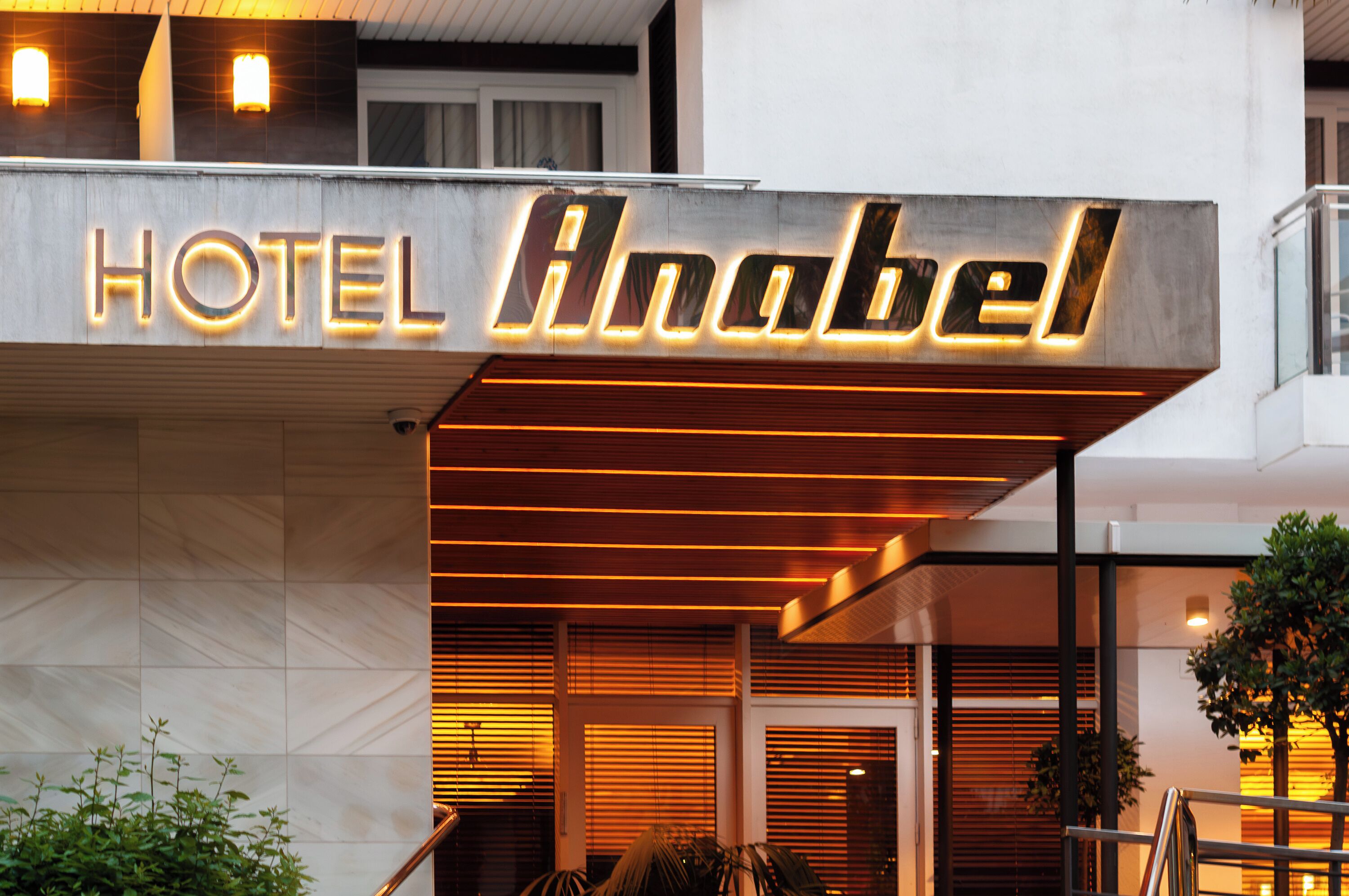 A hotel entrance with a modern design, featuring a prominent illuminated sign that reads 'HOTEL Anabel.'