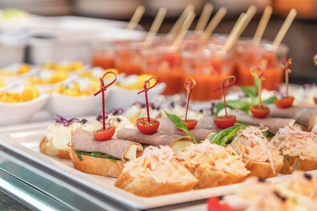 A buffet with various food items including sandwiches, salads, and tomato-based dishes.