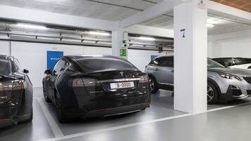 A parking garage with multiple cars, including a black Tesla Model S.