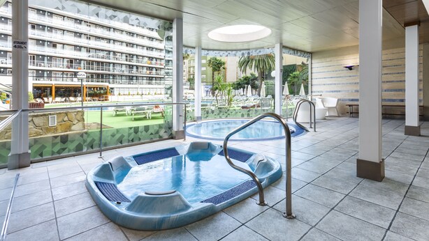 Zona de piscina con jacuzzis y vistas a un hotel.