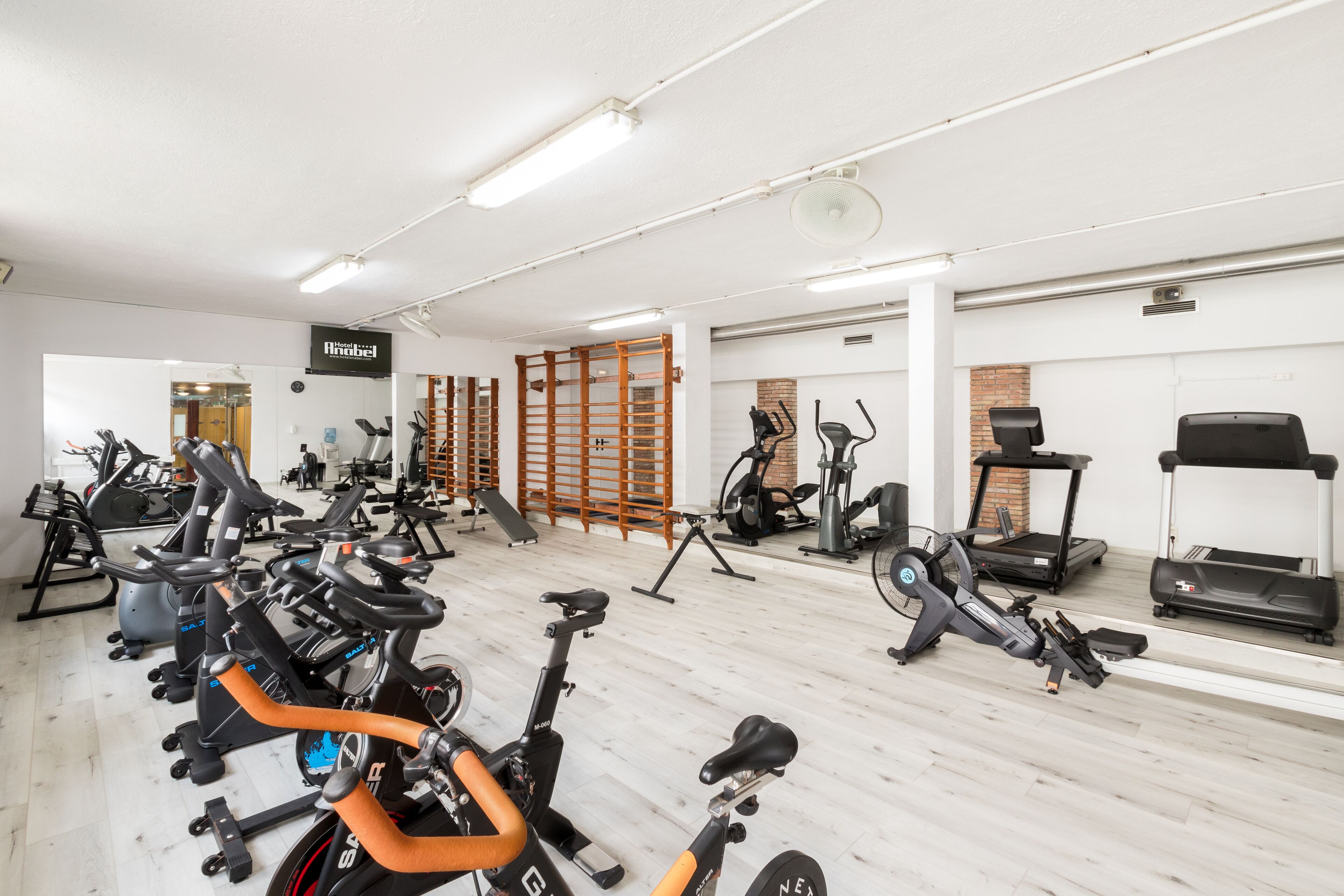 Une salle de sport équipée de divers appareils d’exercice, notamment des vélos d’appartement, des tapis de course et des appareils de musculation elliptique.