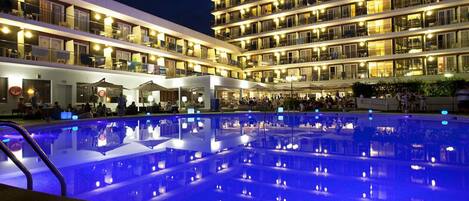A multi-story hotel with a pool area featuring illuminated blue lighting.