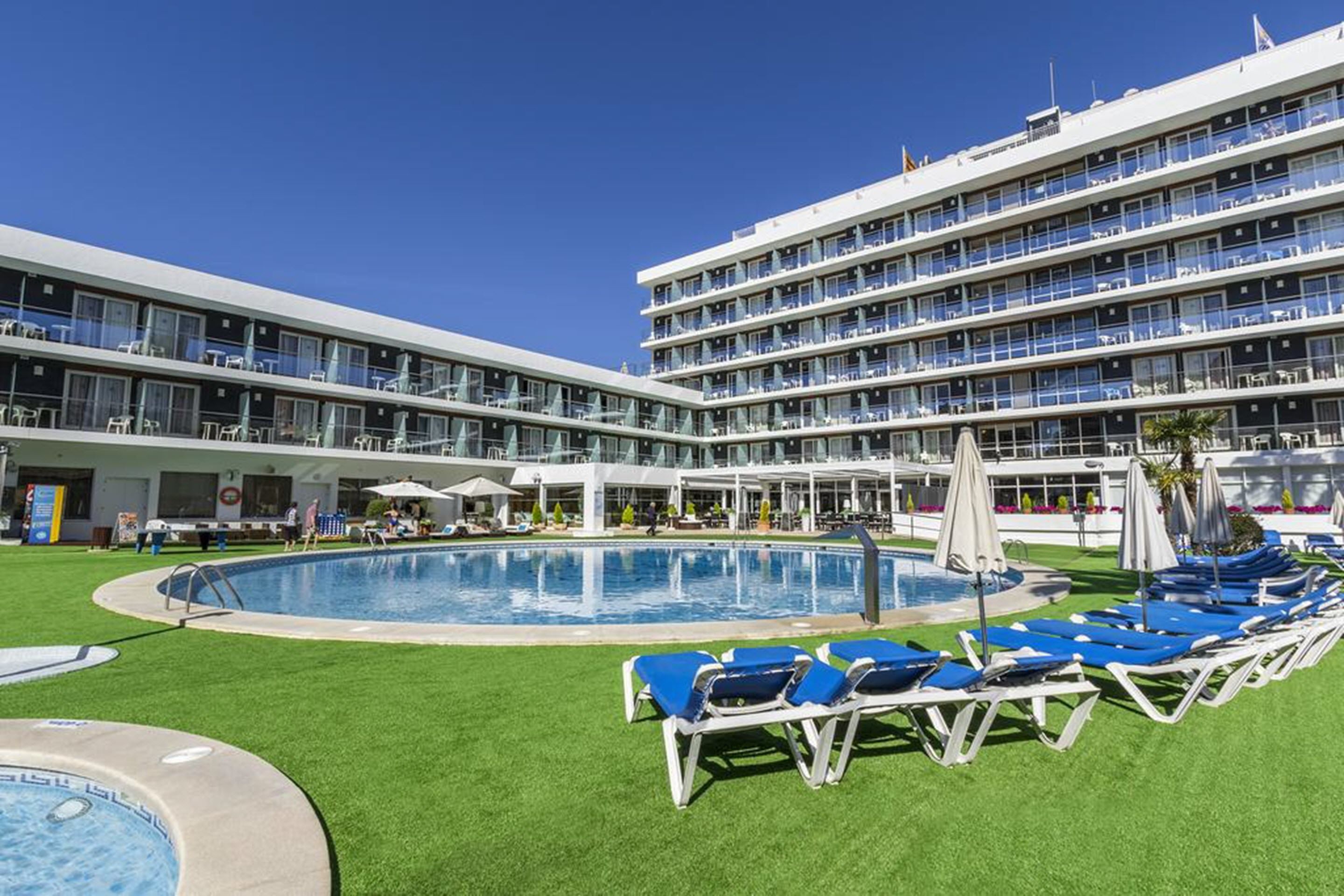 A hotel with a swimming pool, multiple balconies, and outdoor seating areas.