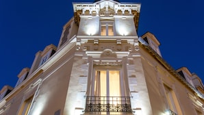 Un edificio histórico con detalles arquitectónicos ornamentales, un balcón destacado y un cielo despejado al fondo.