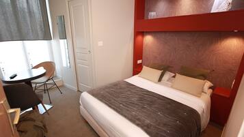 Quarto com cama, escrivaninha e cadeira.