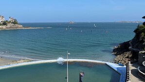 Vista costera con cielo despejado, costa rocosa y zona para nadar con una bandera.
