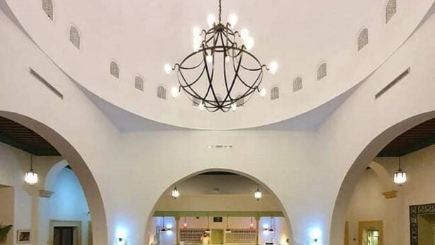 Un vestíbulo amplio con una recepción central, varias zonas de estar y un candelabro.