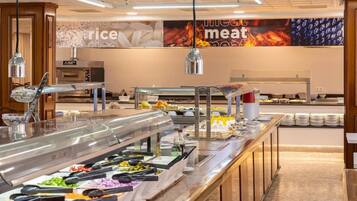 Zona de buffet con diversas opciones de comida, una estación de café y una pared con un anuncio de temática de fuego.