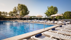 Una piscina con sillones de descanso y sombrillas.