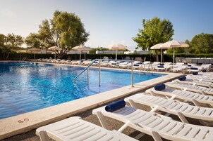 Una piscina al aire libre, sombrillas, tumbonas