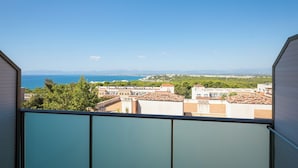 Un balcón con vistas a un paisaje urbano costero, que incluye edificios y el mar.