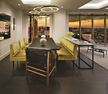 A hotel room with two beds, a nightstand, and a view of a cityscape through a large window. at W Las Vegas