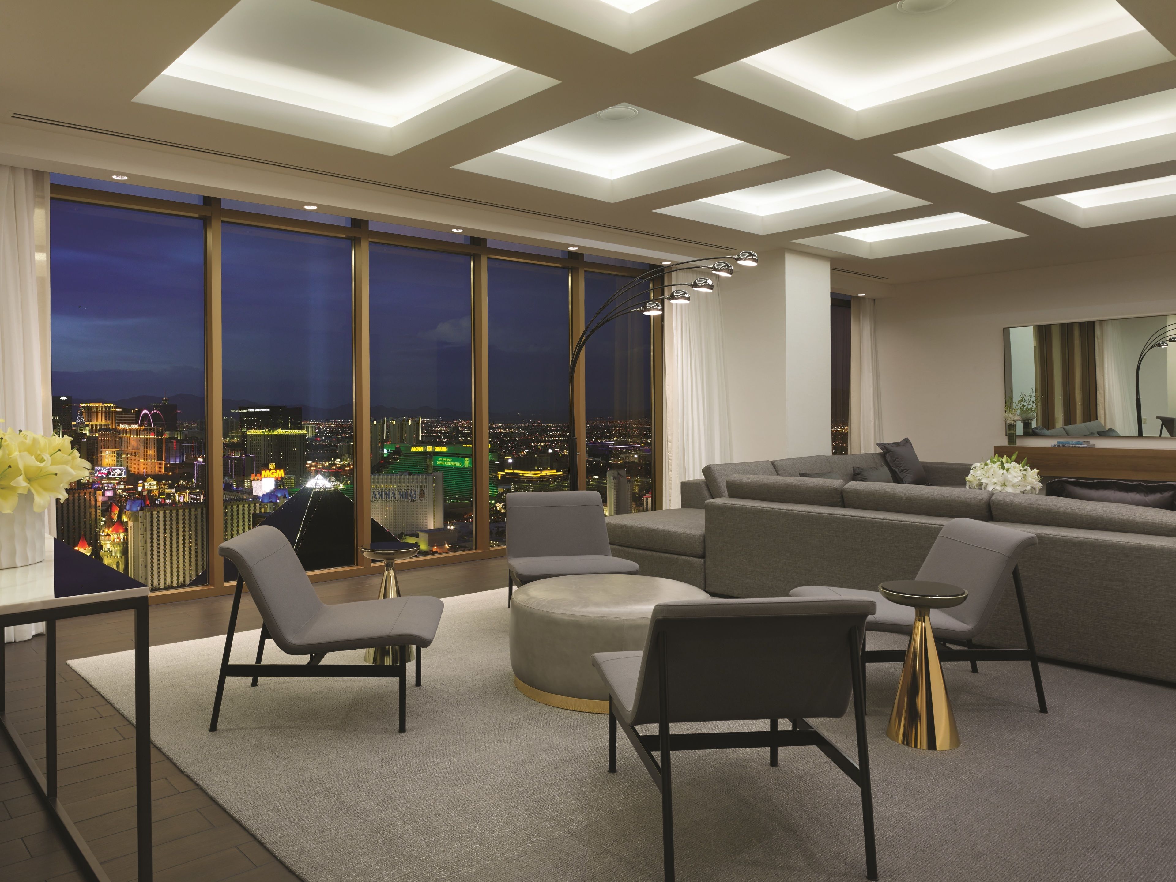 Een moderne woonkamer met uitzicht op de stad, grote ramen en eigentijds meubilair.