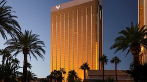 Un edificio alto y moderno con un llamativo logotipo 'W' en la parte superior, rodeado de palmeras.