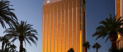 A tall, modern building with a prominent 'W' logo on top, surrounded by palm trees.