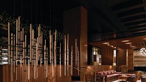 Un interior moderno con paneles de madera, una zona de bar y un área de descanso con sofá y sillones.