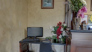 A workspace with a computer, chair, and decorative items including a vase with flowers and a statue. - The Inn At Salmon Creek (Vancouver)