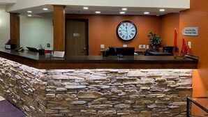 A reception area with a stone wall, wooden reception desk, and a clock on the wall.