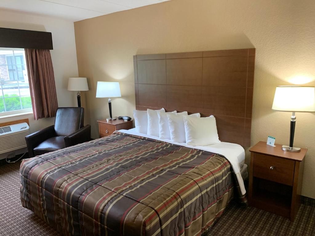 Una habitació d'hotel amb un llit, una cadira, un escriptori i una finestra.
