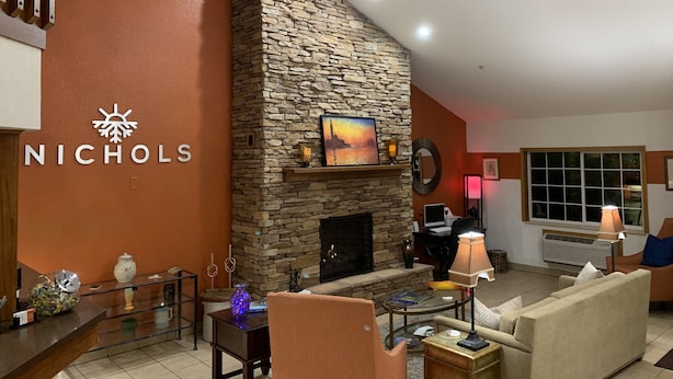 A modern living room with a stone fireplace, a ceiling fan, and a large window.