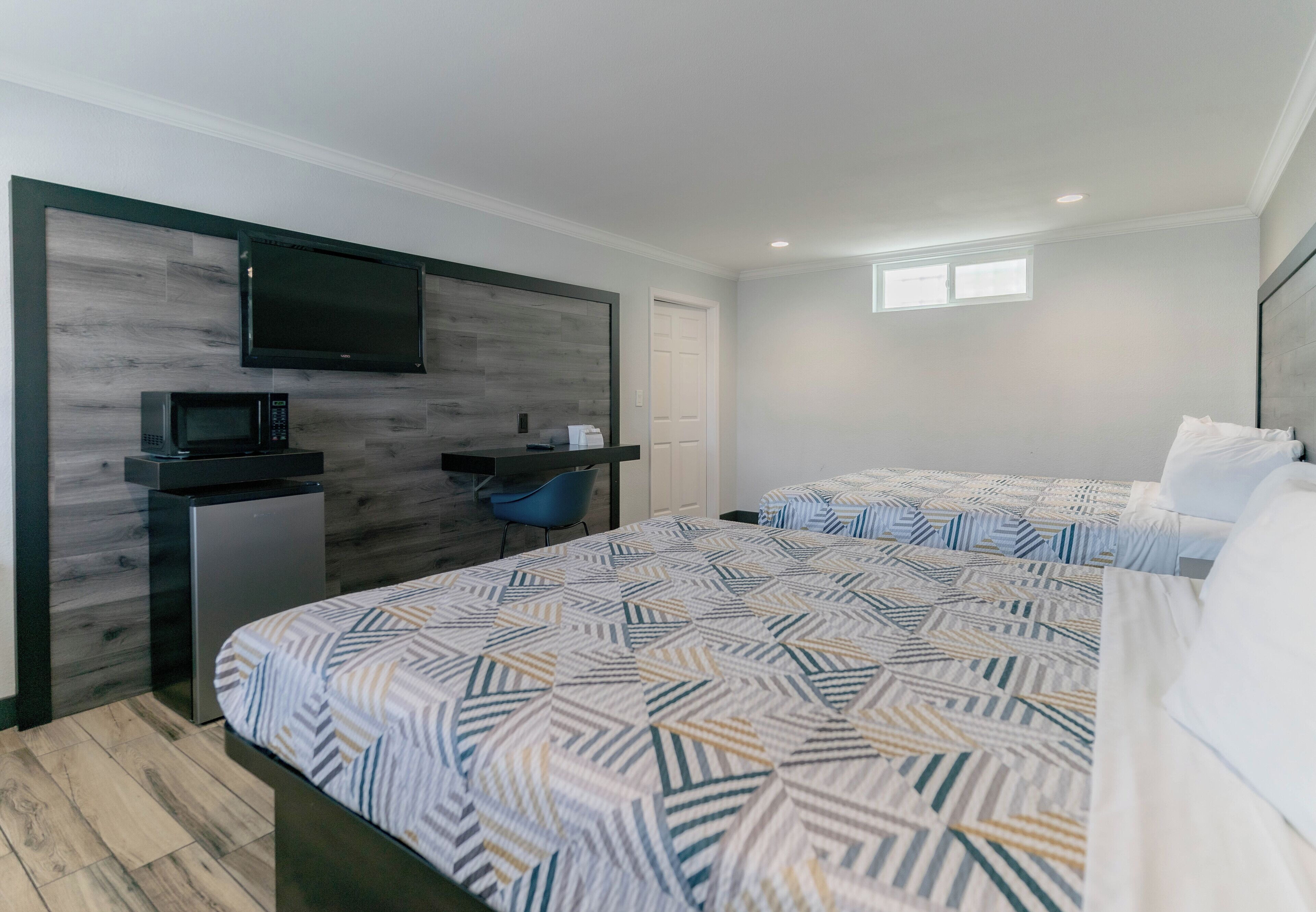 Un dormitorio moderno con una cama grande, un televisor montado en la pared, un escritorio pequeño y una silla.
