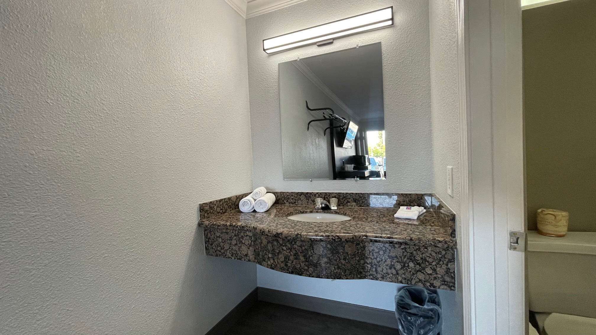A bathroom with a granite countertop, white sink, and a mirror above it.