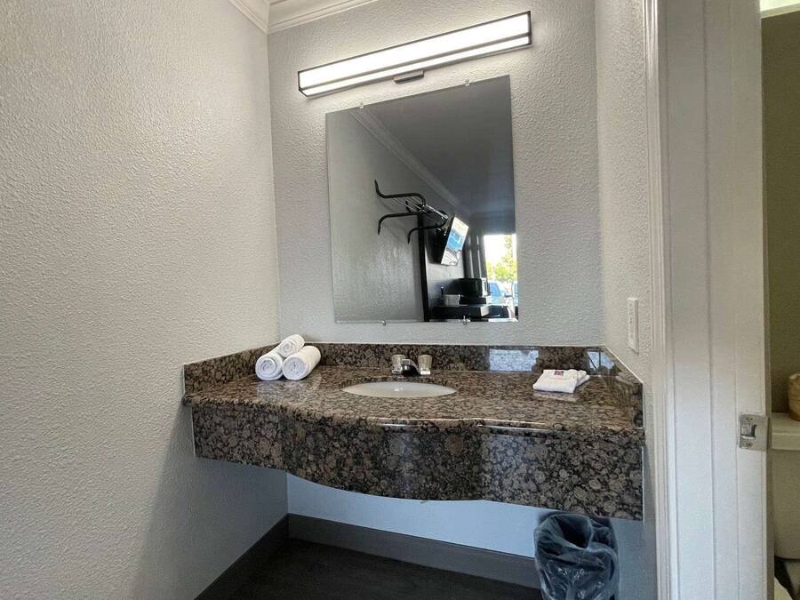 Ein Badezimmer mit Granitplatte, weißem Waschbecken und einem Spiegel darüber.