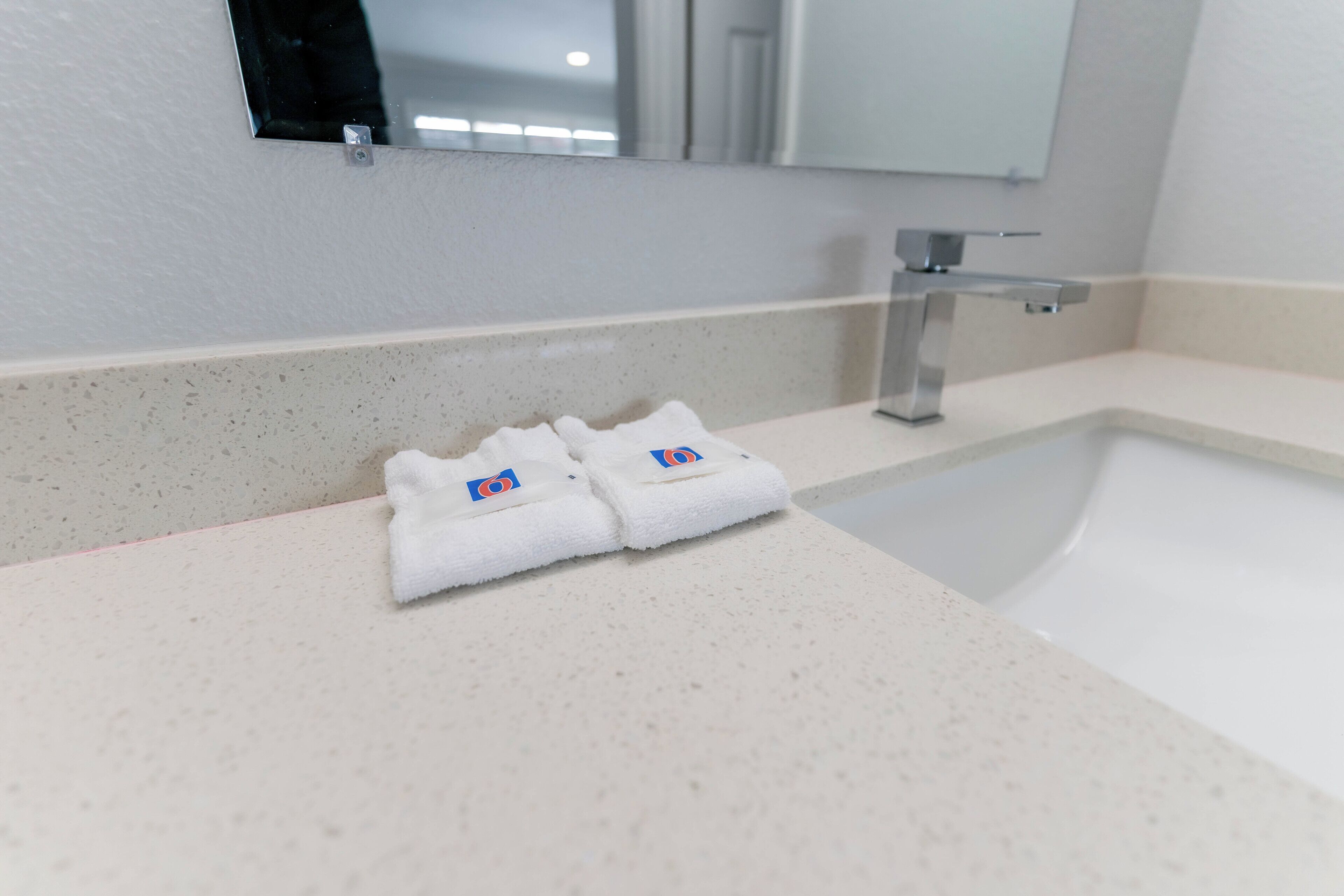 Un baño con lavamanos, espejo y dos toallas dobladas en la encimera.