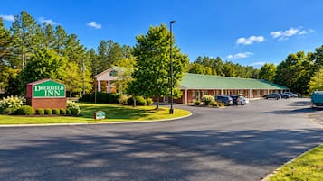 A Deerfield Inn with a green sign, a brick building, and a parking lot with cars.