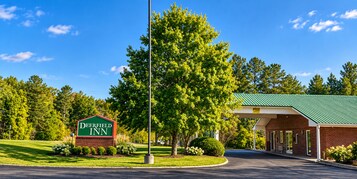 El Deerfield Inn con un letrero verde, una zona de estacionamiento techada y un césped bien cuidado.