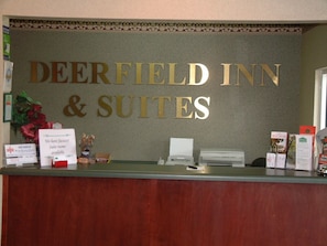 Mostrador de recepción en Deerfield Inn & Suites con un cartel que indica que hay habitaciones con jacuzzi disponibles.