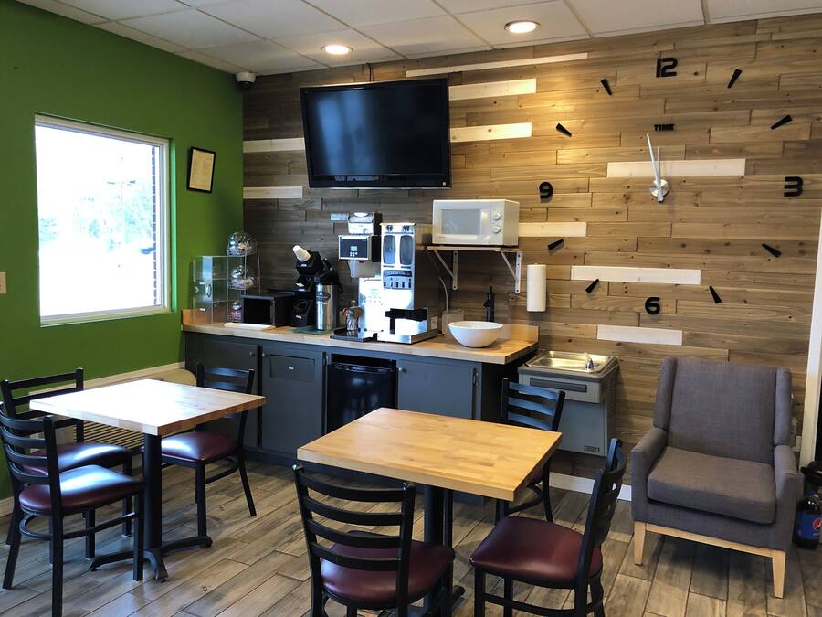 Un restaurant avec une horloge murale en bois, un téléviseur à écran plat, une machine à café et un bol posé sur le comptoir.