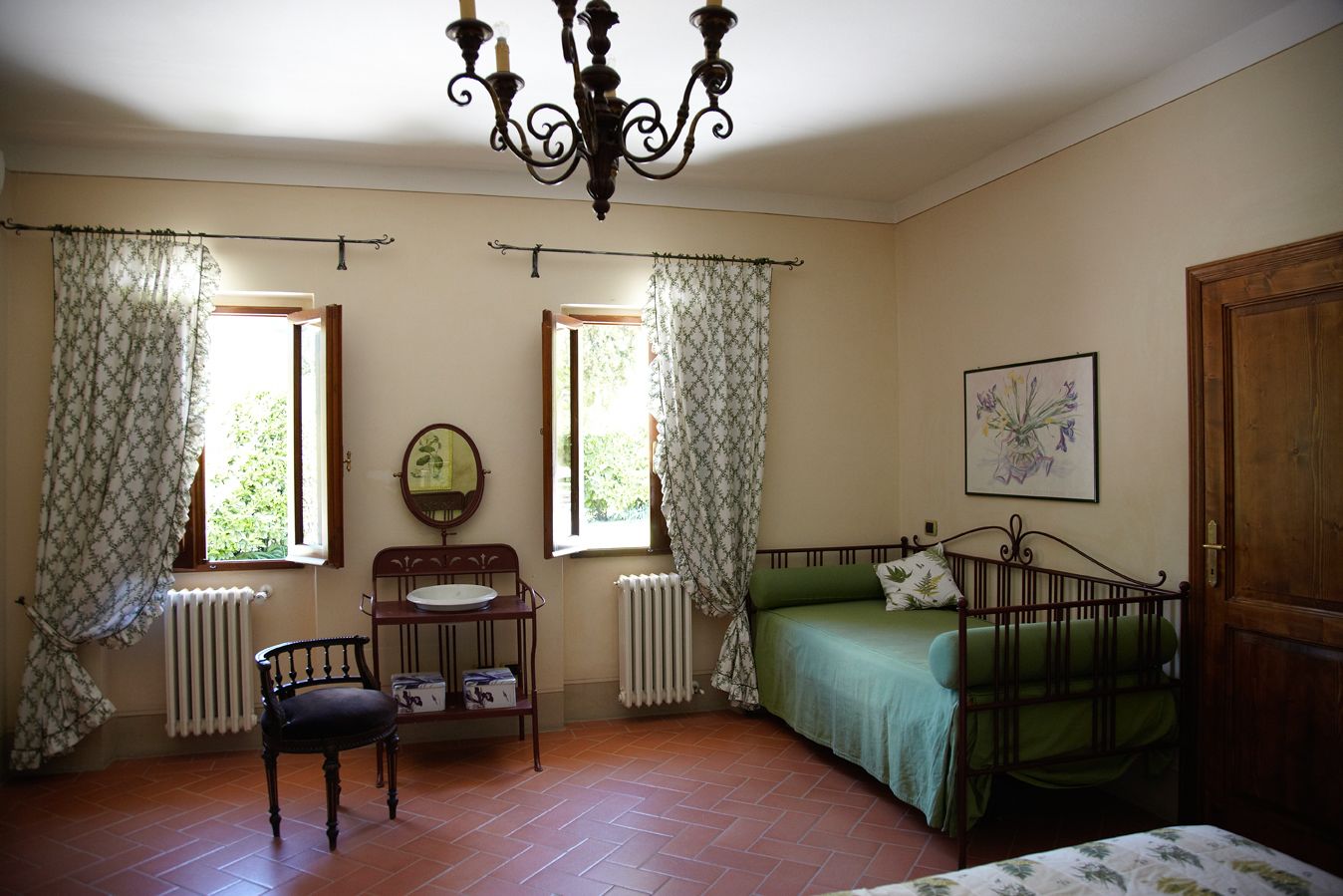 A room with a bed, a chair, a table with a mirror, and a radiator.