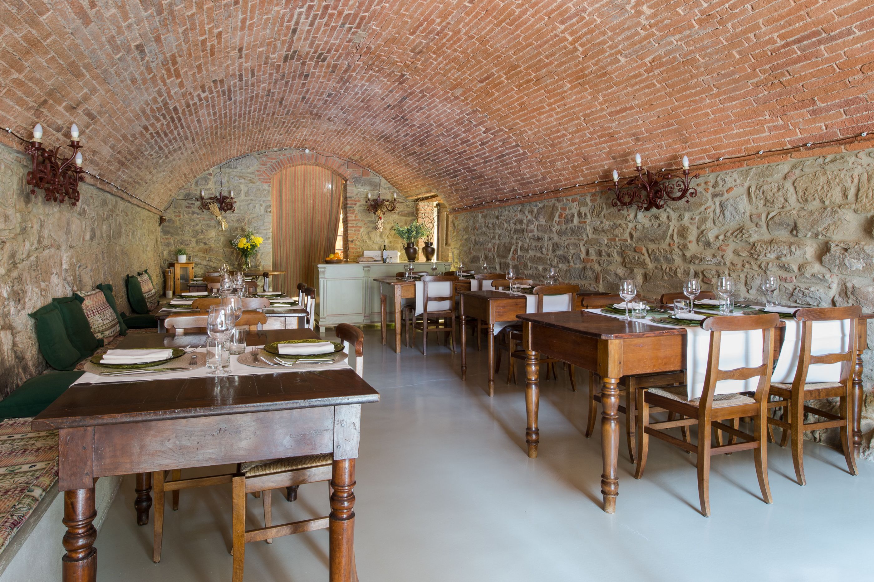 A dining area with brick walls, wooden tables, and chairs.