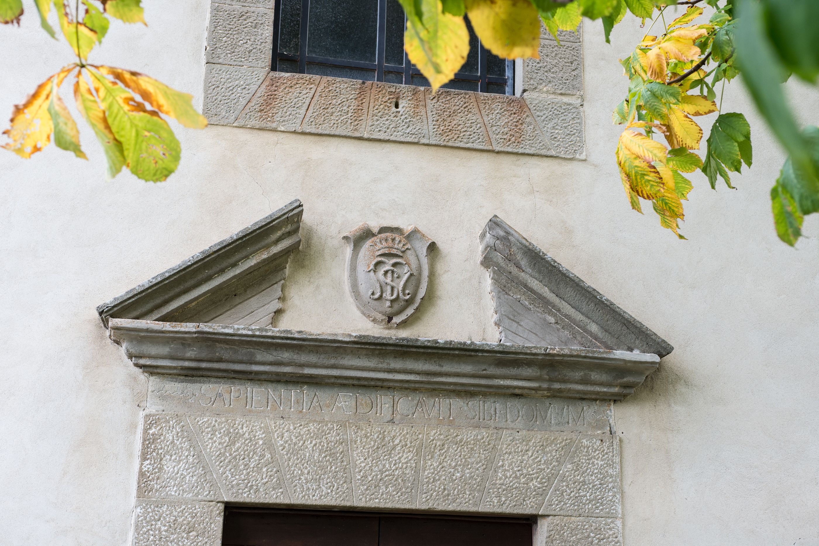 Fachada de pedra com um emblema esculpido e a inscrição "SAPIENTIA EFFICAVIT SIBDOM".