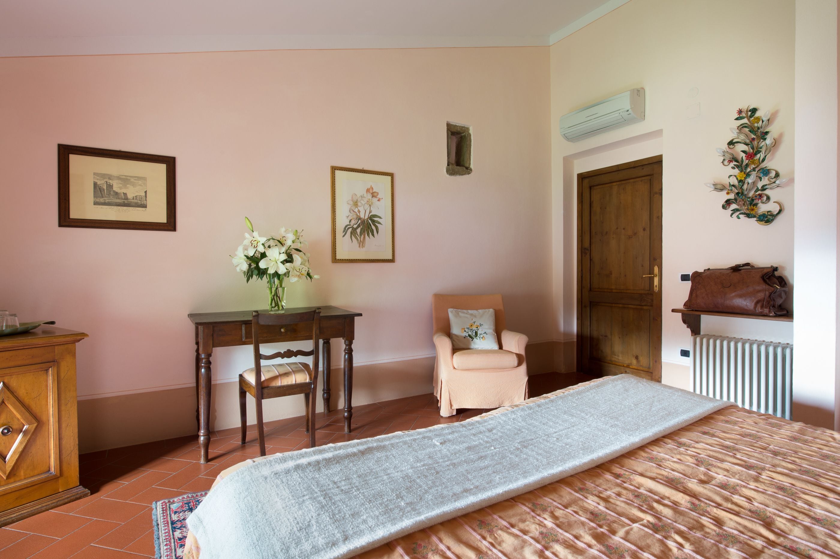 A bedroom with a bed, a desk, a chair, a radiator, and a door.