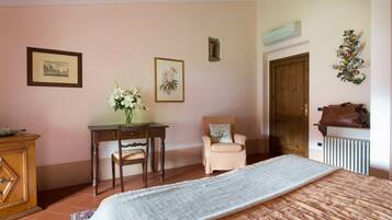 A bedroom with a bed, a desk, a chair, a radiator, and a door.