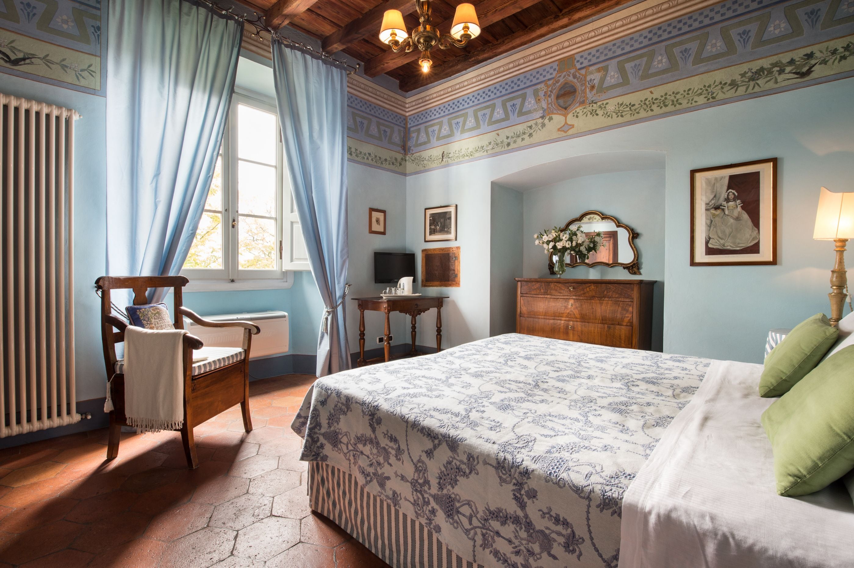 A bedroom with a large bed, a wooden chair, a desk, and a dresser.