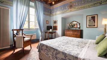 A bedroom with a large bed, a wooden chair, a desk, and a dresser.