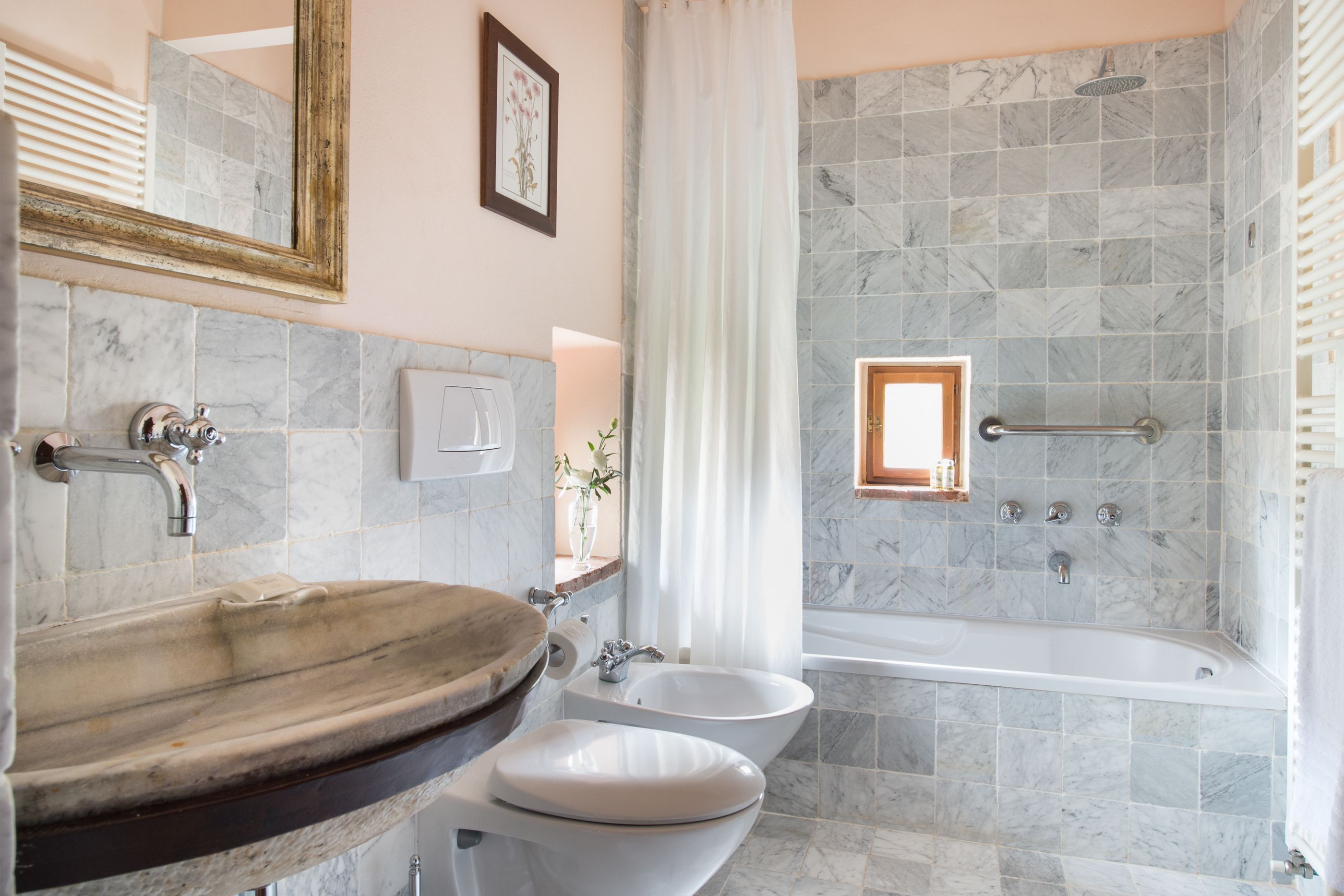A bathroom with a marble sink, two toilets, a bathtub, and a shower.