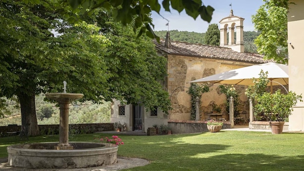 A courtyard with a fountain, a pergola with flowers, and a building with a bell tower. - Relais Villa Belpoggio - Residenza d'Epoca (Loro Ciuffenna)