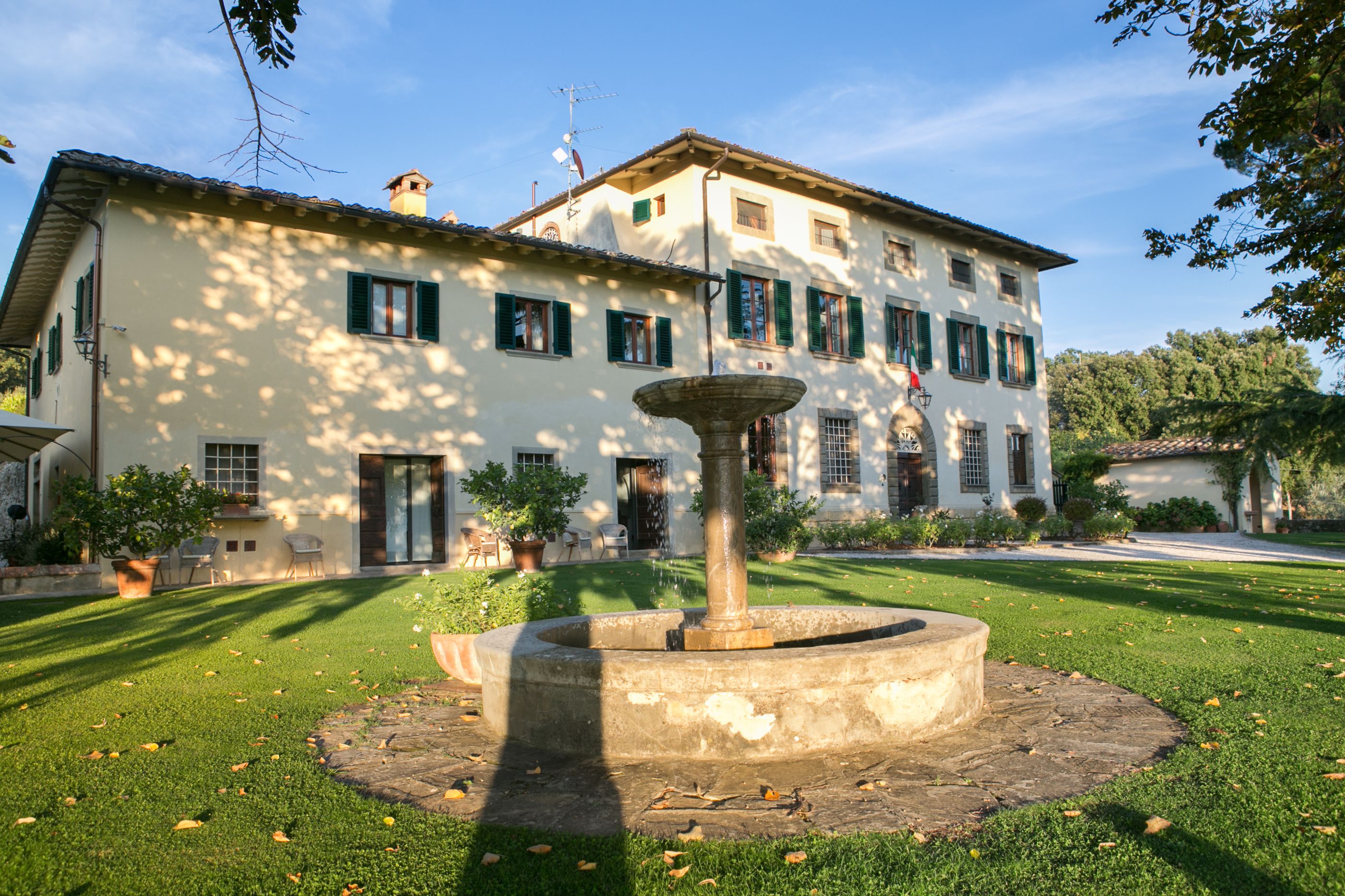 A large building with a fountain in the center of a well-maintained lawn.