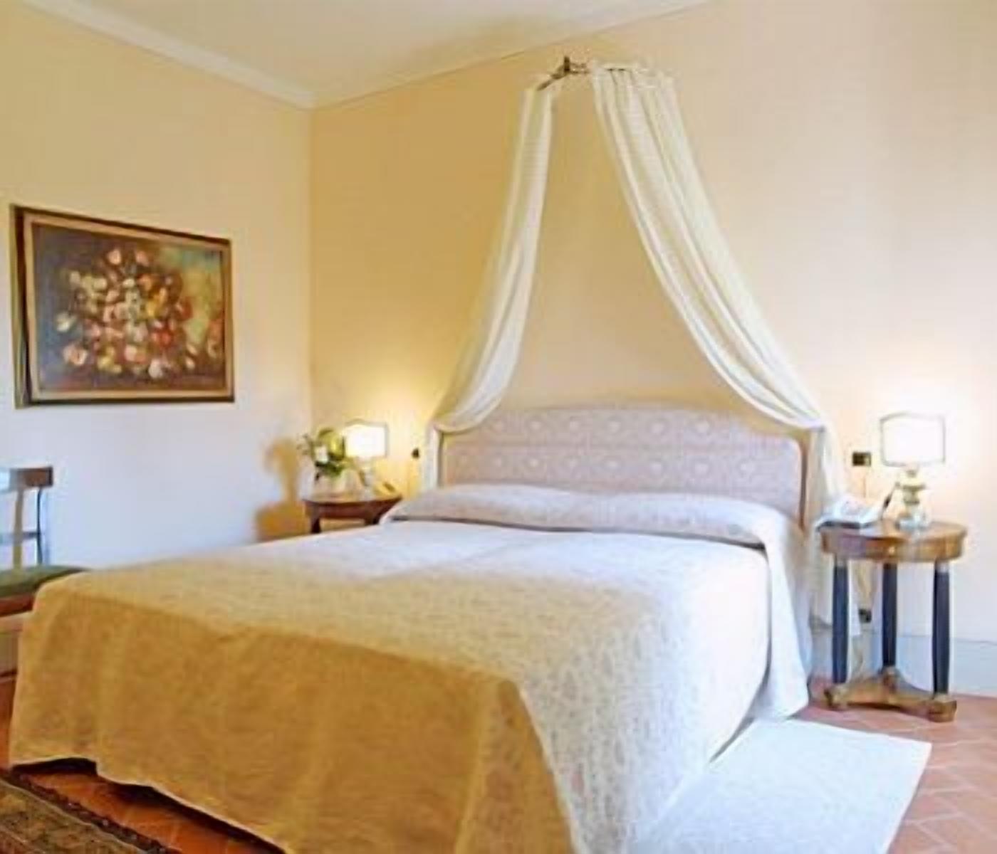 Una camera da letto con un letto a baldacchino, un quadro appeso al muro e due abat-jour.