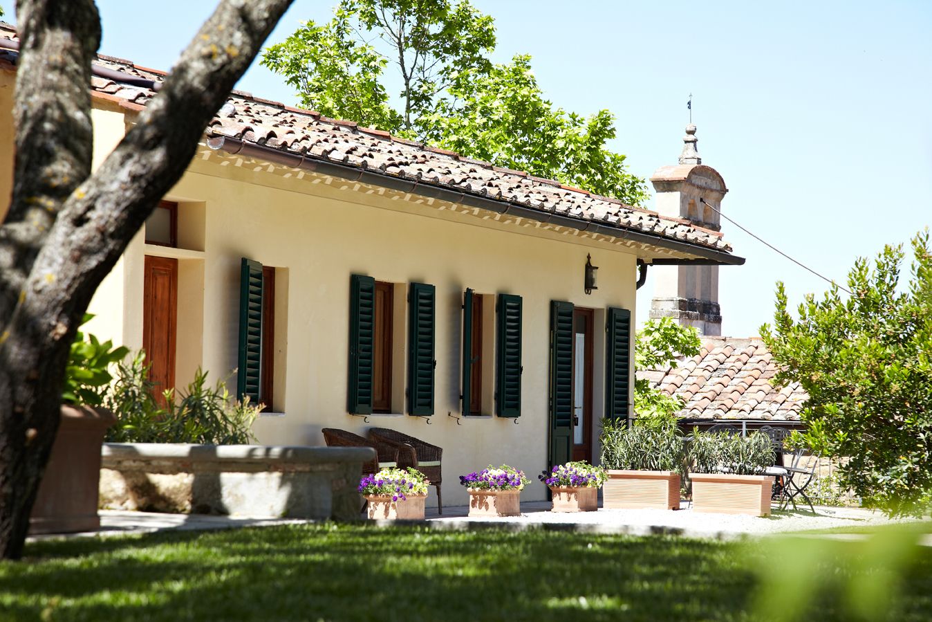 A building with a tiled roof, green shutters, and a bell tower.